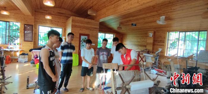 李昌隆(右一)向村屯大学生讲解织布机结构和操作方式。　庞万雯 摄