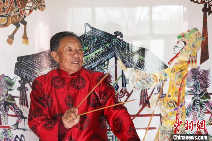 唐山皮影艺人李绍民在家里的墙上耍皮影。朱大勇 摄