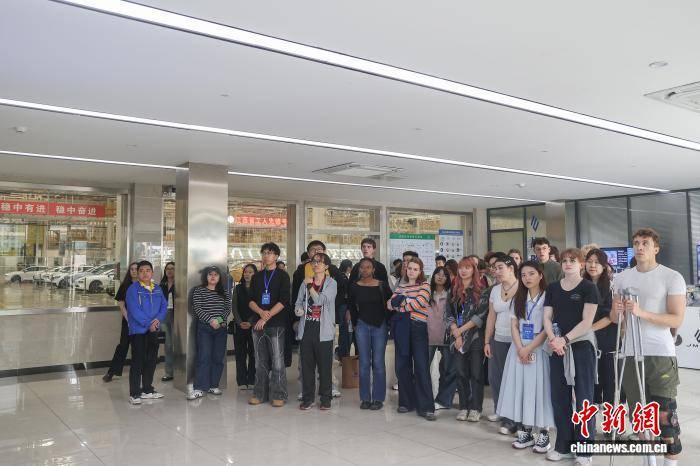 中外青年學(xué)生在車間門口聆聽介紹